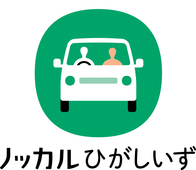 ノッカルひがしいず(緑色の円の内に助手席に人を乗せた白い車を運転している人のシルエットのロゴマーク)