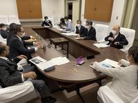 約10名程のマスク姿の文教厚生常任委員会員が、楕円形の机の上に資料を広げながら意見交換を行っている様子の写真