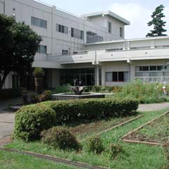 植木や花壇の奥に白を基調とした校舎が見える東伊豆町立熱川小学校の外観写真