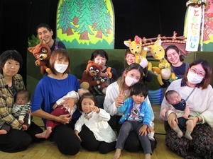 人形劇のセットの前に集まっている子供たちや保護者の方、演者の方々の写真