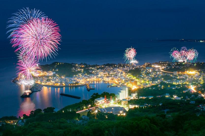 伊豆稲取の夜景と夜空に打ちあがるたくさん大きな花火の写真