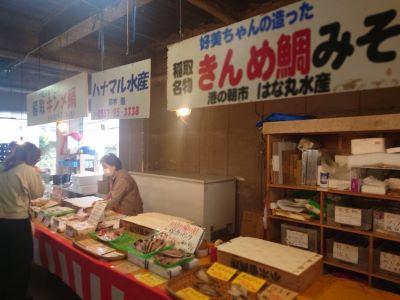 朝市で商品を販売する店員さんと買い物客の写真