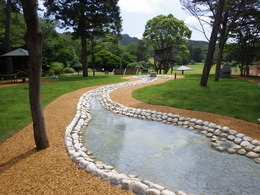 芝生の公園の生にある、きれいに整備された浅い水路の写真