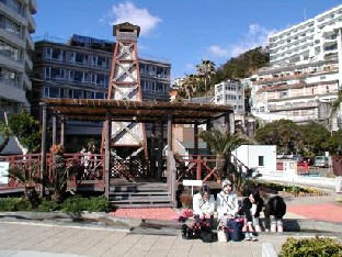 宿泊施設に囲まれた櫓や足湯を楽しんでいる観光客の様子の写真