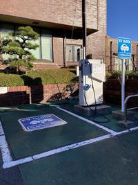 駐車場の一角に設けられた電気自動車急速充電器の傍に急速充電器用案内サインの標識が設置され、駐車スペースに記されたマークの写真